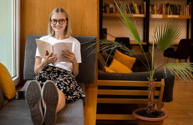 Молодой студент читает книгу в библиотеке
