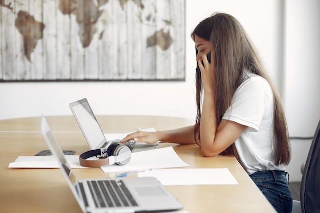 Il giovane studente che si siede alla tavola e usa il computer portatile