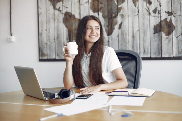 Young student sitting at the table and use the laptop