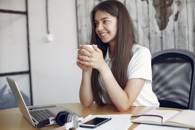 Foto gratuita il giovane studente che si siede alla tavola e usa il computer portatile