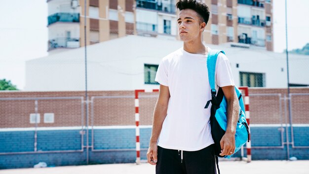 Young student with backpack on schoolyard