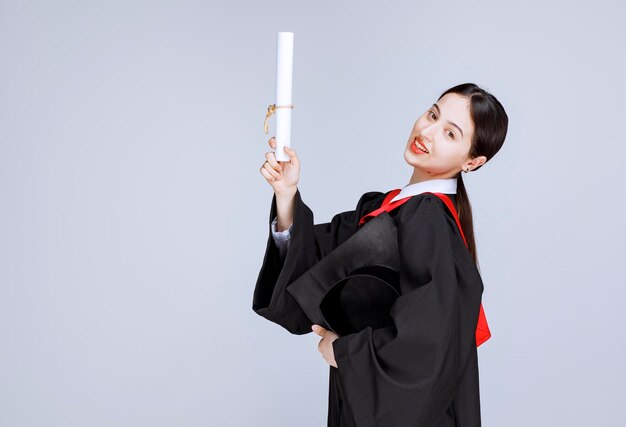 Young student with gown and diploma posing for graduation day. High quality photo
