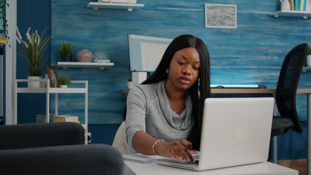 Young student working remote from home at marketing strategy writing financial graphs on notebook