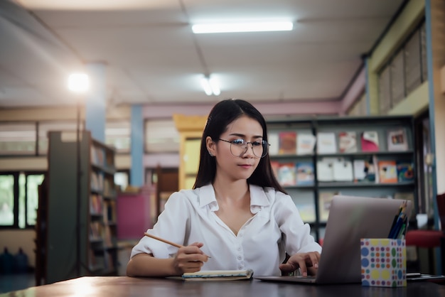 学んでいる若い学生、図書館の本棚