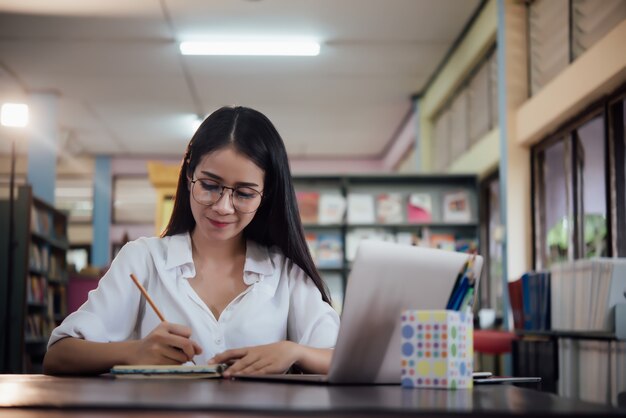 学んでいる若い学生、図書館の本棚