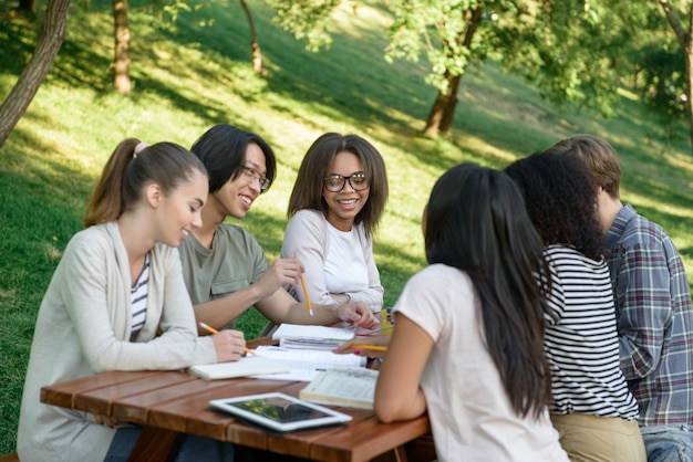 座っていると話しながら屋外で勉強する若い学生