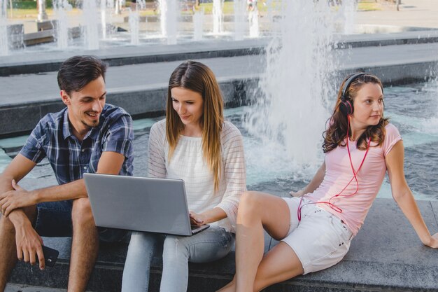 Молодые студенты с ноутбуком в парке