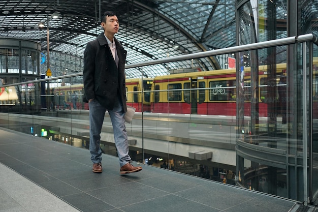 Giovane uomo d'affari asiatico alla moda che cammina con sicurezza attraverso la stazione della metropolitana moderna