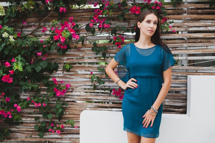 Free Photo young stylish beautiful woman in blue dress, summer fashion trend, vacation, garden, tropical hotel terrace, smiling