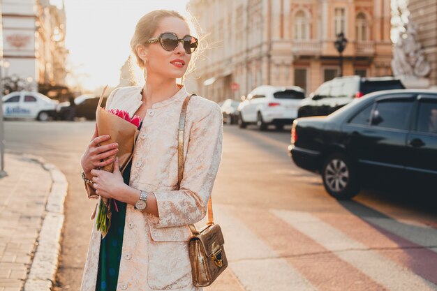 Young stylish beautiful woman walking on city street on sunset
