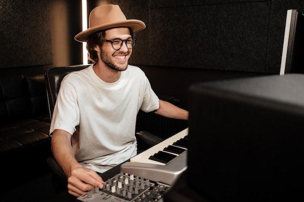 Giovane musicista allegro ed elegante che lavora felicemente al nuovo album nel moderno studio di registrazione del suono