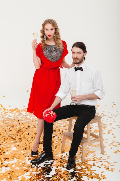 Young stylish couple in love holding glasses and drinking champagne, celebrating new year