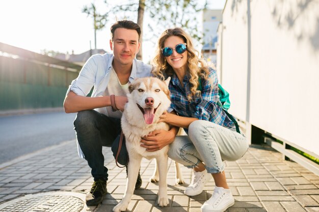 通りで犬とポーズをとって若いスタイリッシュなカップル