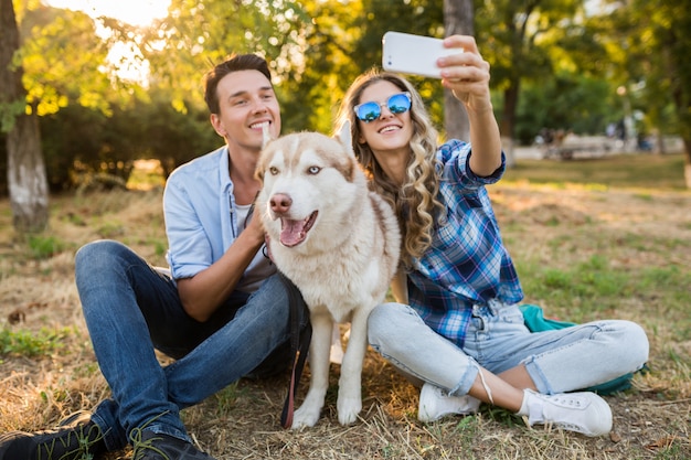 通りで犬を連れて歩いてスタイリッシュなカップル。男と女のハスキー犬と一緒に幸せ