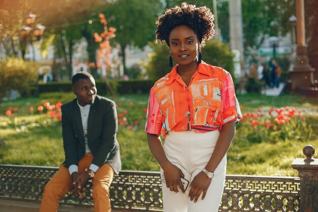 A young and stylish dark-skinned couple sitting in a sunny city