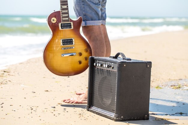 young stylish guy on the beach with musical instruments,the concept of music and relaxation