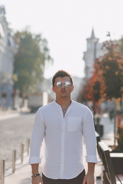 Молодой стильный парень в рубашке шел по европейской улице в солнечный день