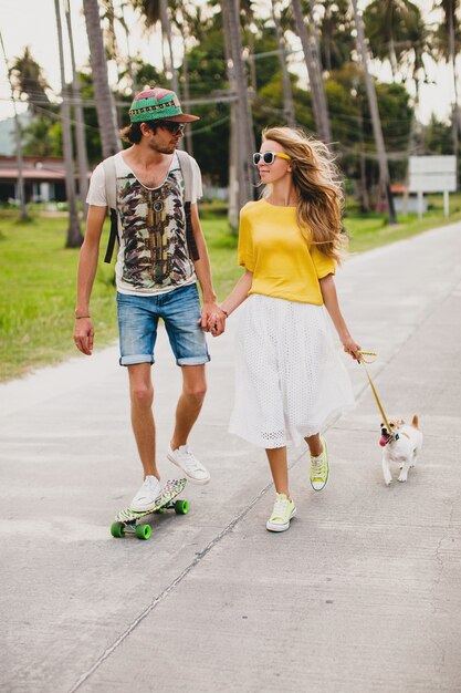 Молодая стильная хипстерская влюбленная пара на отдыхе с собакой и скейтбордом, развлекаясь