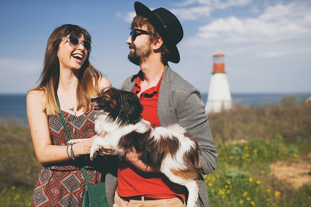 Free photo young stylish hipster couple in love walking with dog in countryside