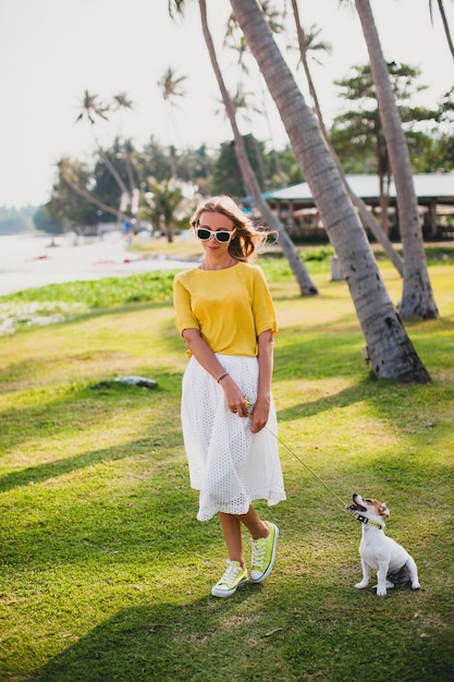 Young stylish hipster woman holding walking and playing with dog at the baech