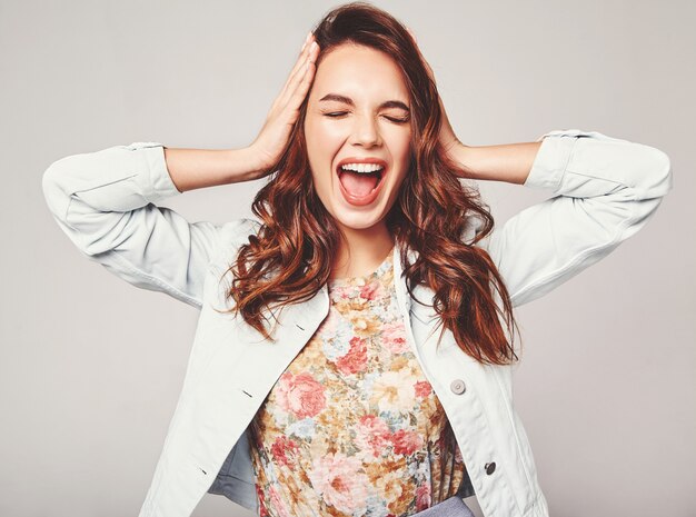 young stylish laughing model in colorful casual summer clothes with natural makeup on gray and