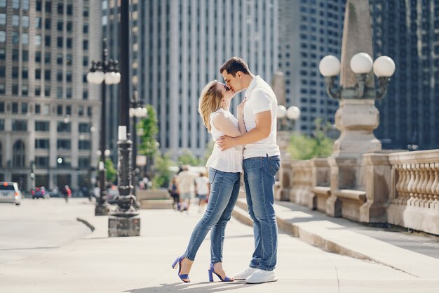 young and stylish lovers couple in white t-shirts and blue jeans walking in a big city 