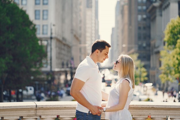 若いとスタイリッシュな愛好家のカップルは、白いTシャツと青いジーンズは、大都市で歩いて