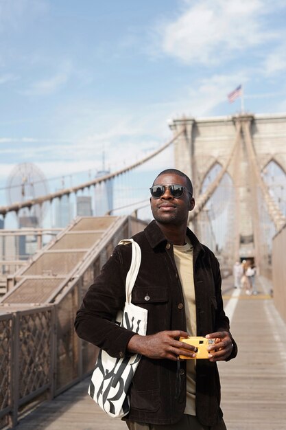 Young stylish male photographer using camera while exploring the city