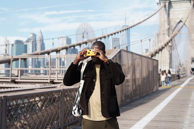Young stylish male photographer using camera while exploring the city