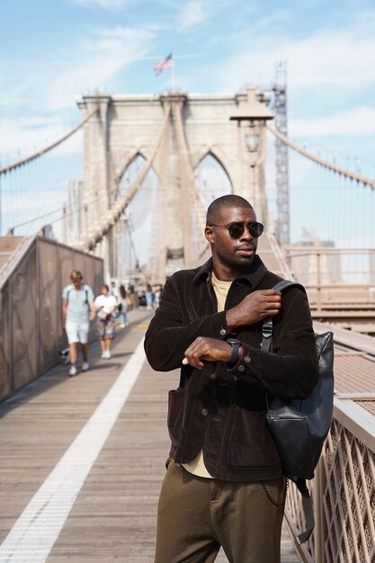 Young stylish man exploring a city bridge by himself