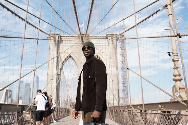 Foto gratuita giovane uomo alla moda che esplora da solo un ponte della città