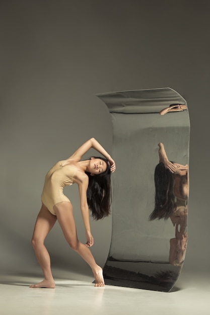 Free photo young and stylish modern ballet dancer in front of a mirror