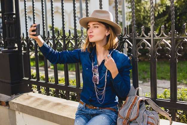 Foto gratuita giovane donna graziosa alla moda che prende un selfie, vestito in jeans e camicia di jeans