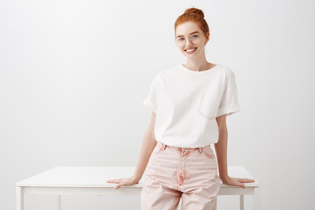 Free photo young stylish redhead girl smiling, leaning on table