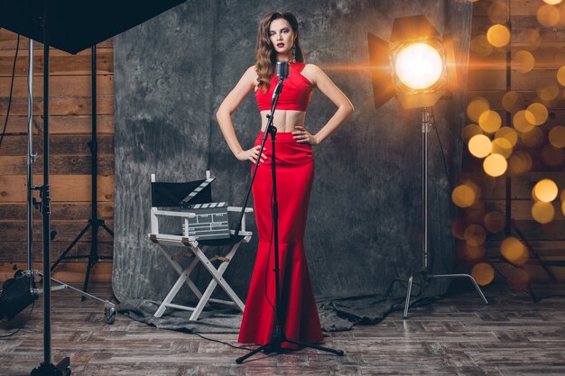 Young stylish sexy woman on cinema backstage, celebrating, red satin evening dress