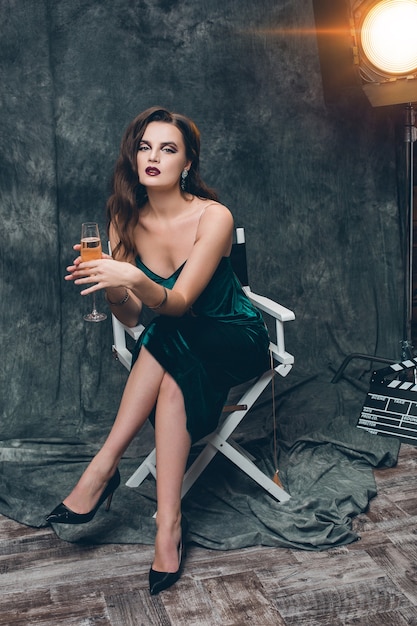 Young stylish sexy woman on cinema backstage, celebrating with a glass of champagne