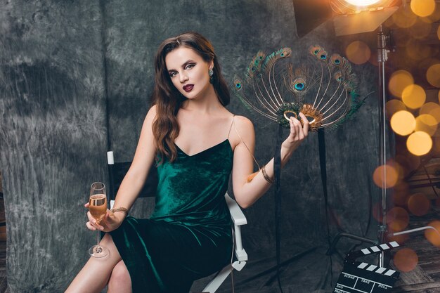 Young stylish sexy woman sitting in chair on cinema backstage