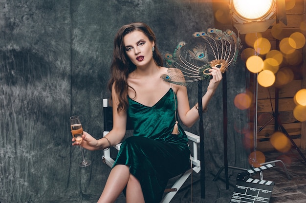 Young stylish sexy woman sitting in chair on cinema backstage