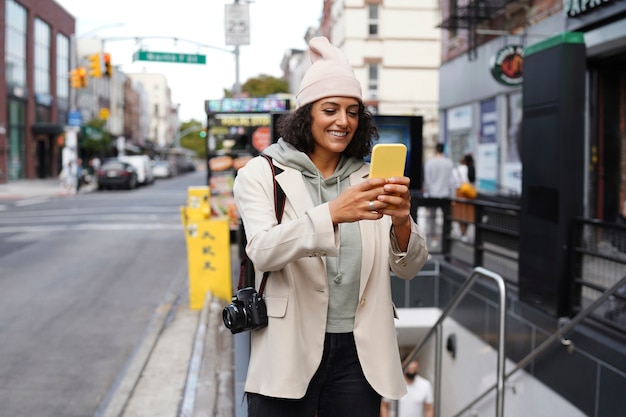 探索にスマートフォンを使用して市内の若いスタイリッシュな女性