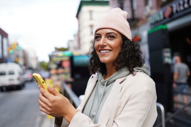 Молодая стильная женщина в городе с помощью смартфона для исследования
