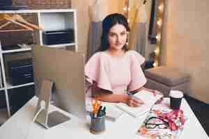 Free photo young stylish woman in pink luxury dress working at office on computer