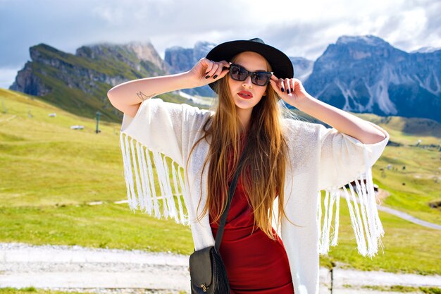 Young stylish woman posing at Alp mountains in boho fashion outfit