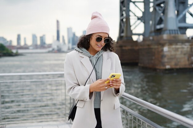 Молодая стильная женщина с помощью смартфона на открытом воздухе, исследуя город