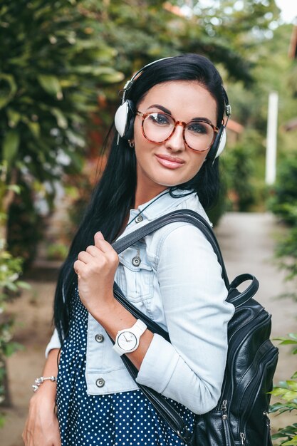 Foto gratuita giovane donna alla moda che cammina con lo smartphone, ascoltando musica in cuffia, vacanze estive