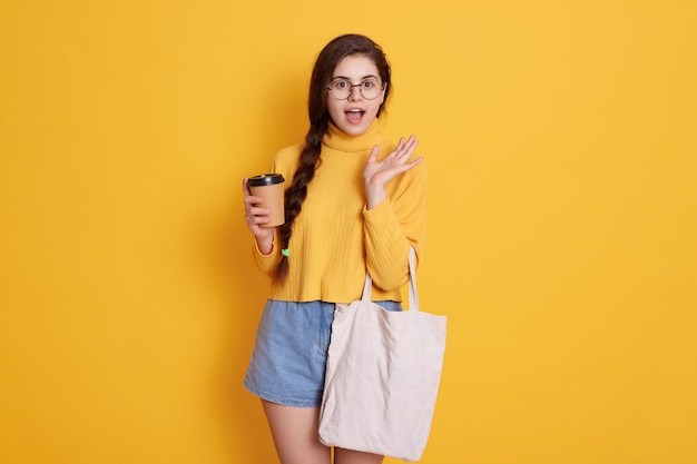 Young stylish young woman wearing shirt and short, lady holding bag and take away coffee