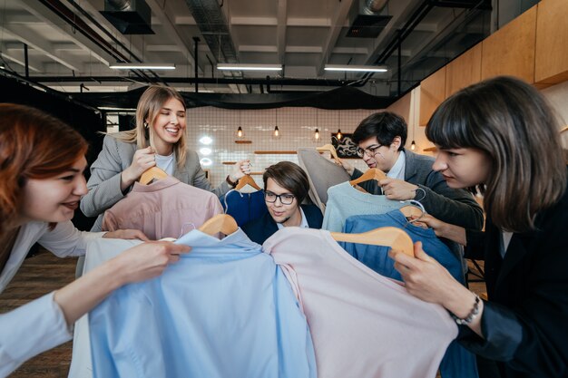 Young stylist looking through set of shirts for fashion shooting