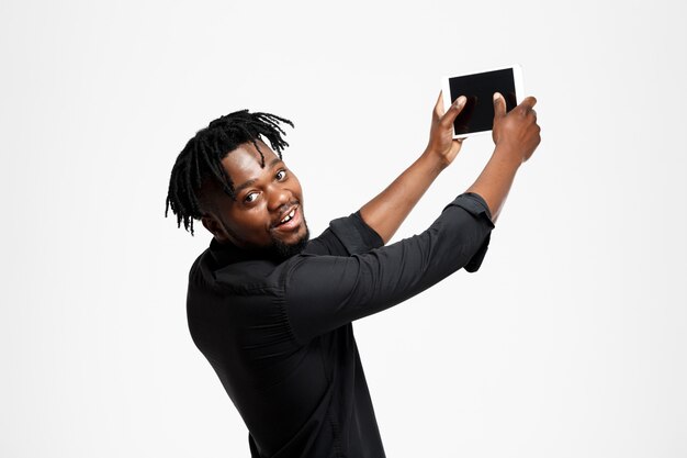 Молодой успешный африканский бизнесмен делая selfie на белизне.
