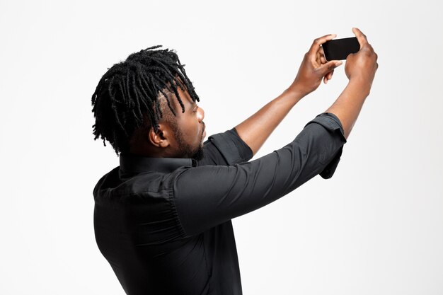 Young successful african businessman making selfie on white.