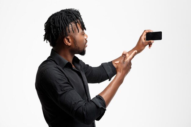 Young successful african businessman making selfie on white.