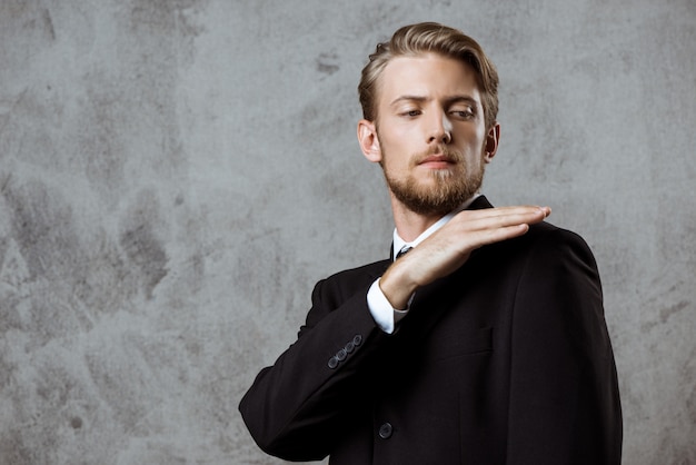 Young successful businessman cleaning jacket